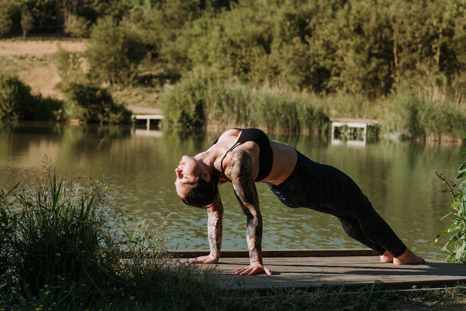 Woman in white clothes doing yoga pose on a wooden dock by a calm lake in the morning